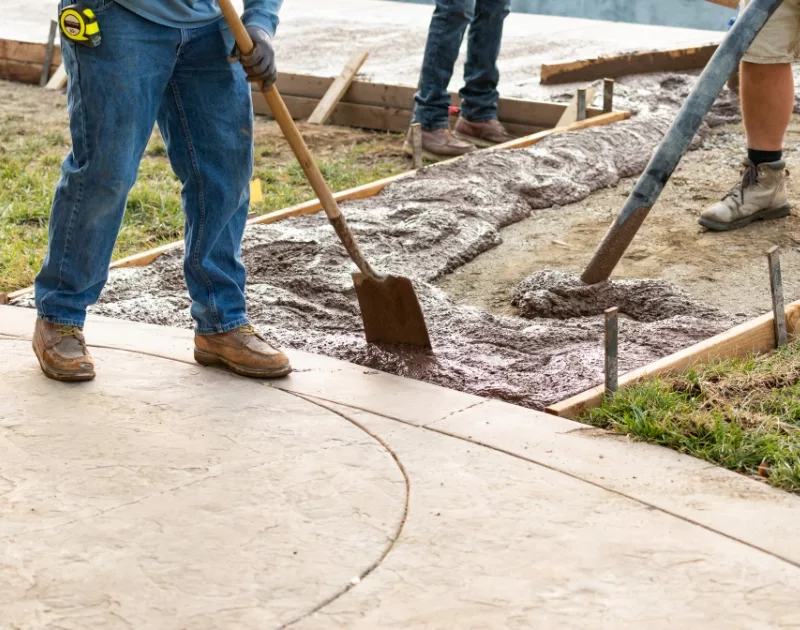 Workers pouring concrete for new sidewalk construction.