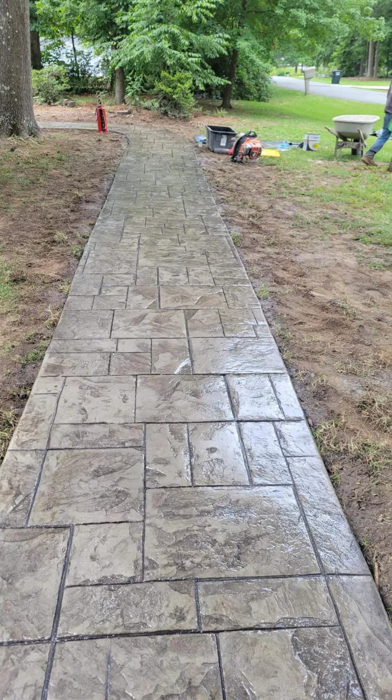 Gray stamped concrete walkway installed beneath mature trees
