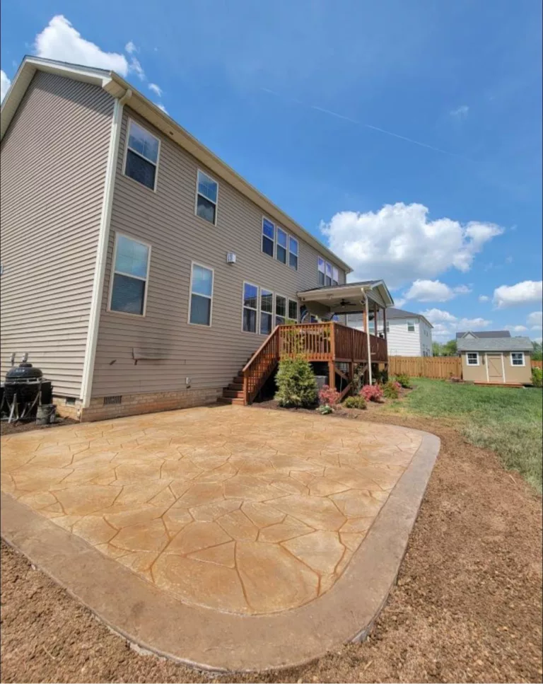 Tan stamped concrete patio behind a two-story home