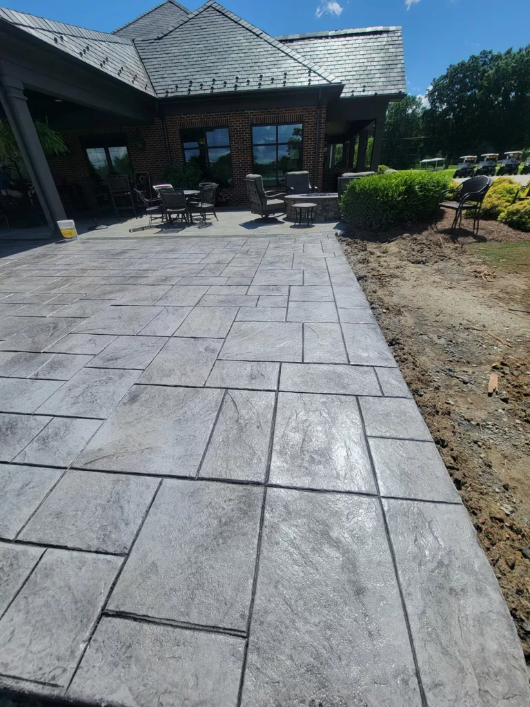 Gray stamped concrete patio leading toward a covered porch