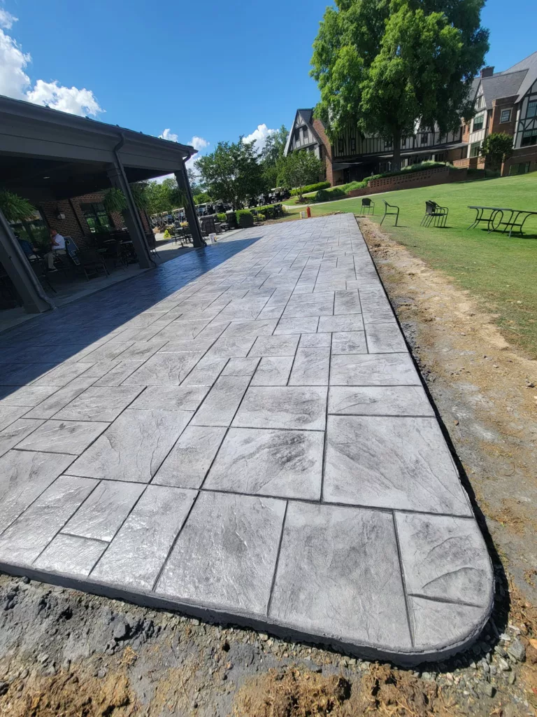 Long gray stamped concrete patio extending across a backyard