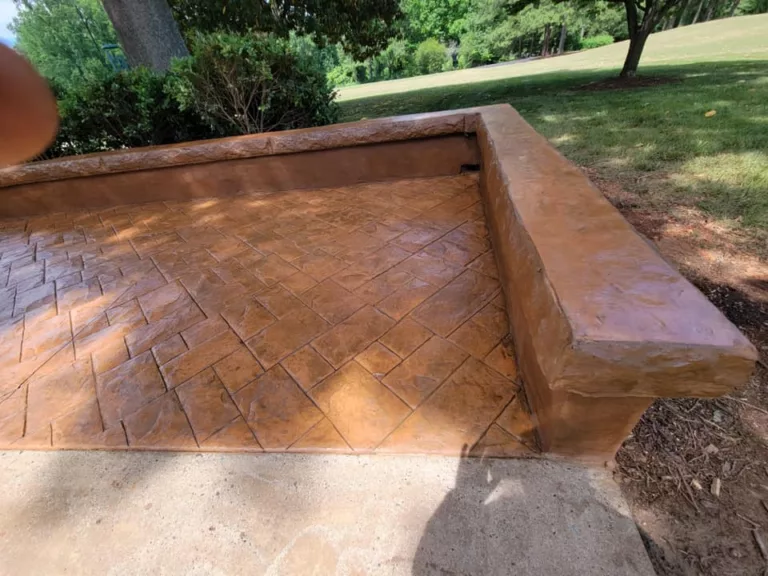 Brown stamped concrete patio with a built-in seat wall