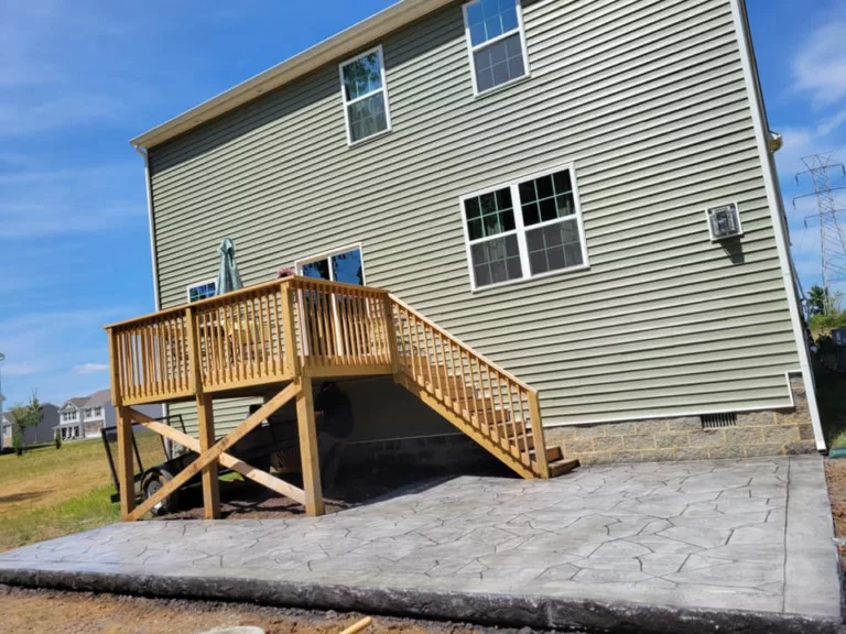 Gray stamped concrete patio installed beneath a backyard deck