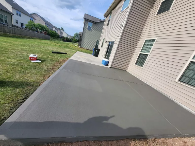 Freshly finished smooth concrete patio along the side of a home