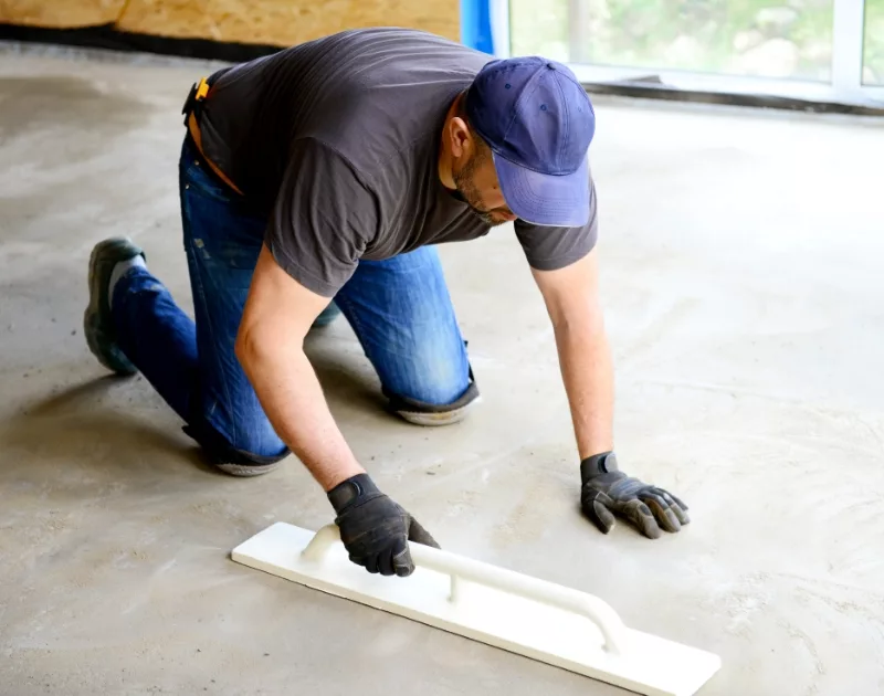 Worker smoothing concrete floor with float tool